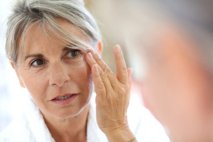 Woman looking at skin in mirror