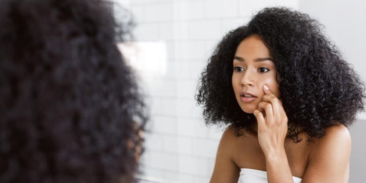 Woman looking at skin in mirror - bad facial