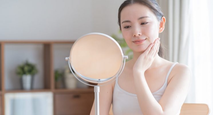 Woman looking at skin in mirror