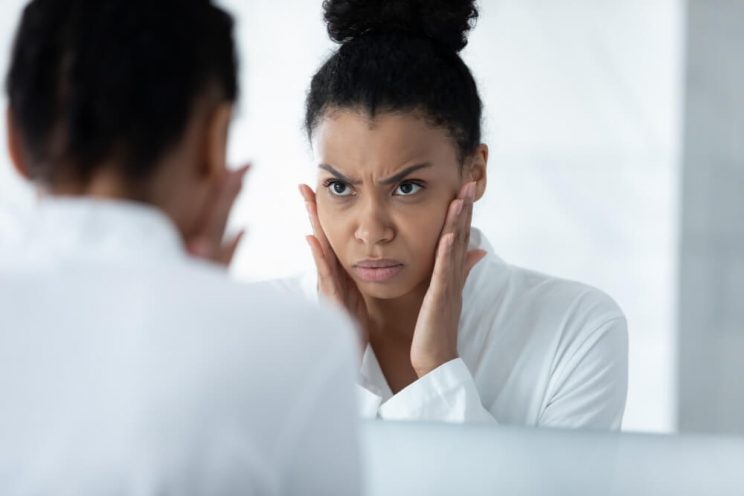 Woman looking at skin in mirror