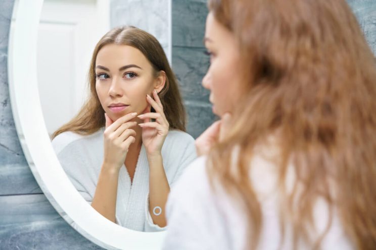 Woman looking at skin in mirror