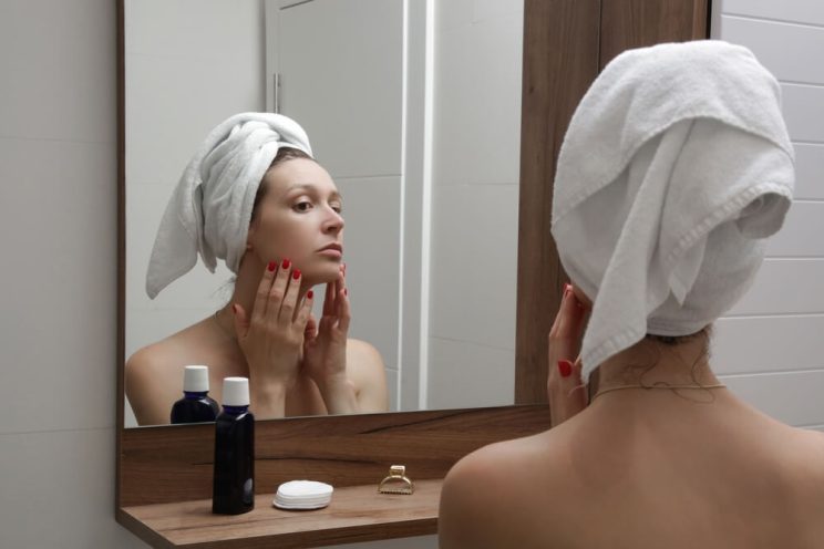 woman looking at skin in mirror